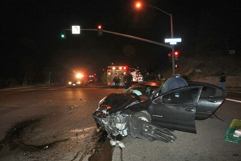 car crash in street intersection at night, ems in background