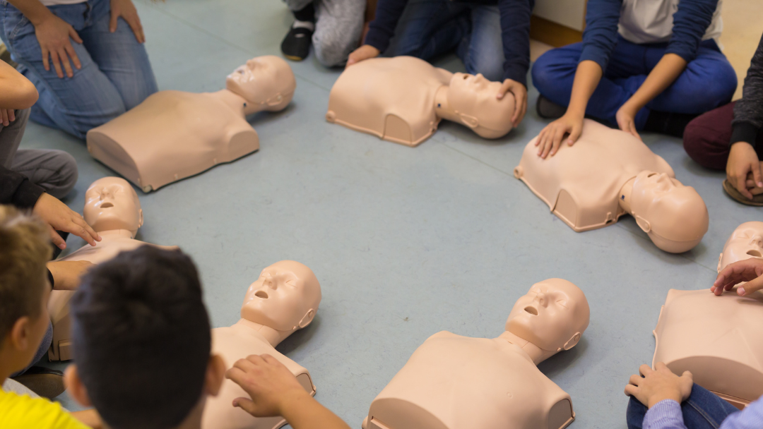 students in circle with cpr manikins