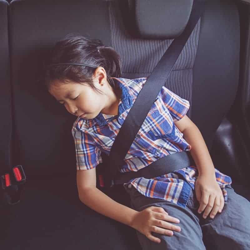 child asleep or unconscious in back seat of car with improper seatbelt positioning