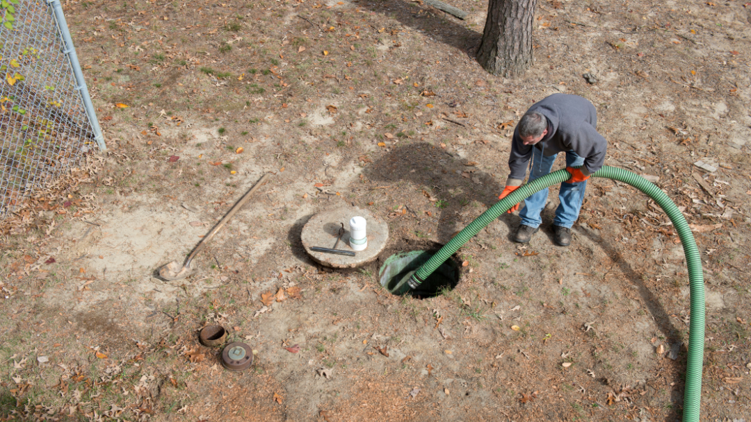 man pumping out septic tank in ground