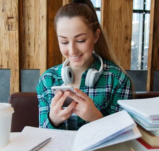 female student studying with smartphone, headphones, notebook