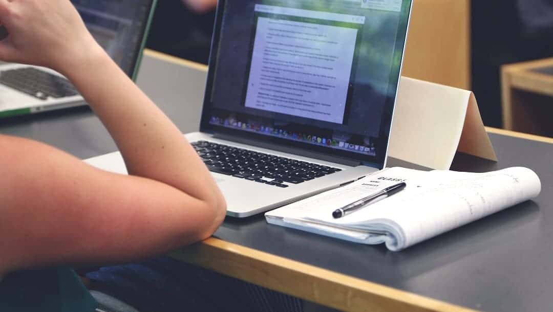 student in front of laptop with notebook