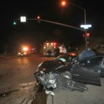 car crash in street intersection at night, ems in background