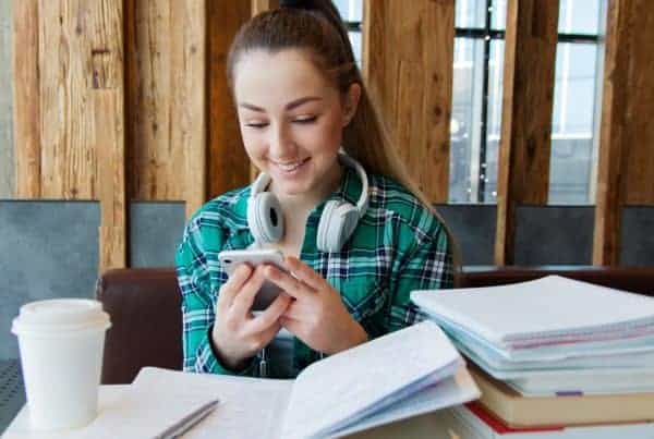 female student studying with smartphone, headphones, notebook