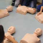 students in circle with cpr manikins