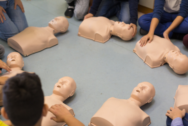 students in circle with cpr manikins