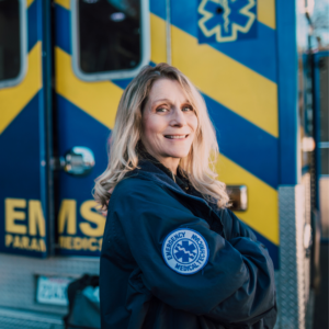 middle aged female EMT smiling in front of ambulance