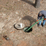man pumping out septic tank in ground