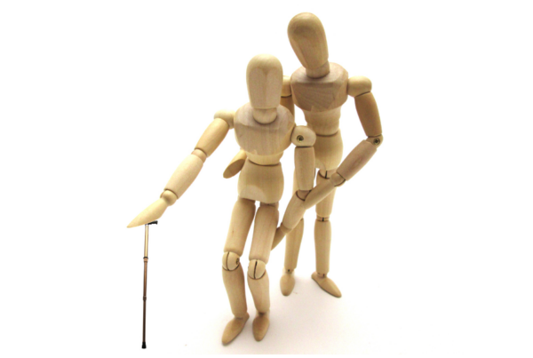 two wooden figures, one with cane, on white background